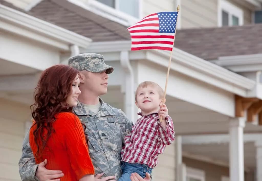 A service member and family on their front porch with an American flag